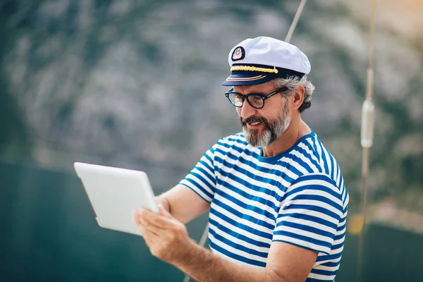 Dospělý muž stojící na palubě své lodi a používá digitální tu — Stock fotografie