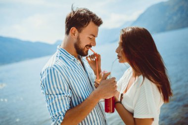 Güzel çift sahilde eğlenmek, kokteyller içme ve