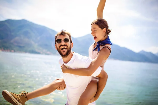 Bonito jovem dando passeio de piggyback para namorada na praia . — Fotografia de Stock