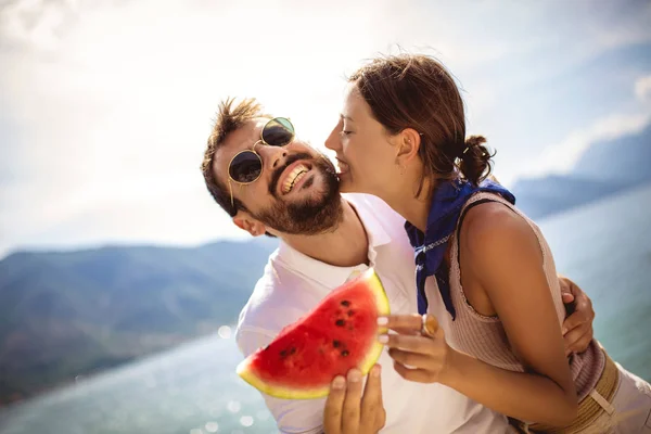 Jovem casal sorrindo comer melancia na praia se divertindo. — Fotografia de Stock