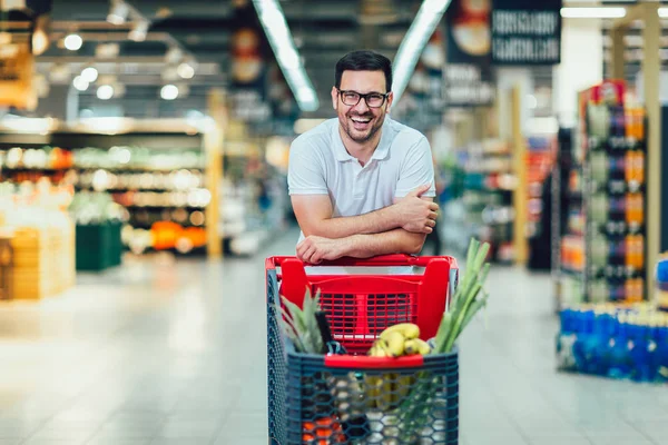 Красавчик в супермаркете толкает тележку и смоллин — стоковое фото