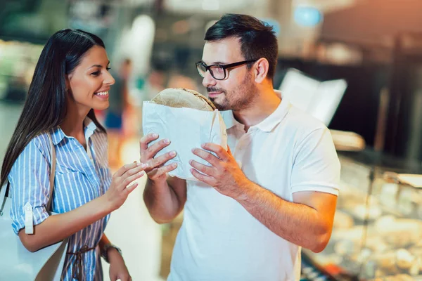 Junges und glückliches Paar, das frisches Gebäck wählt und zusammen steht — Stockfoto