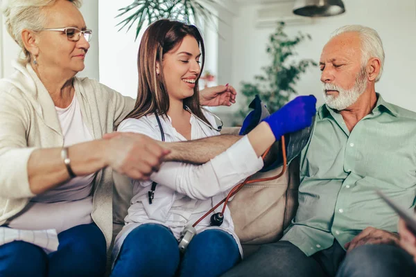 Giovane medico che prende la pressione sanguigna durante la visita a casa — Foto Stock