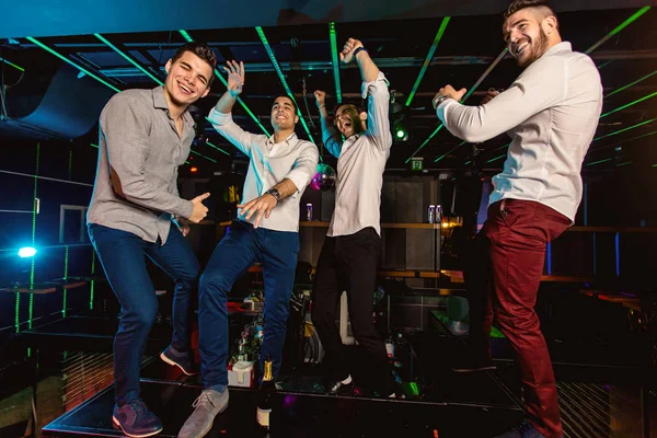 Grupp av leende manliga vänner som har kul i nattklubb — Stockfoto