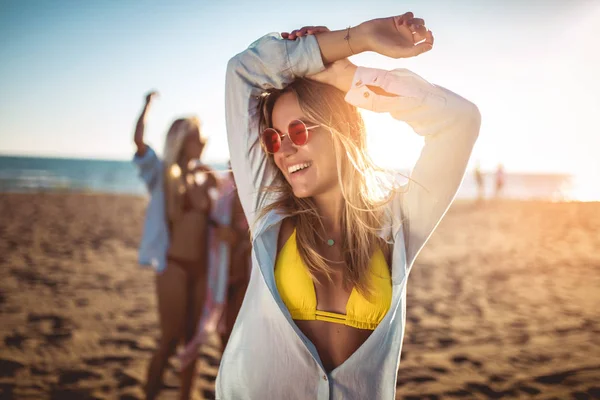 バックグラウンドで彼女の友人とビーチで幸せな若い女性。G — ストック写真