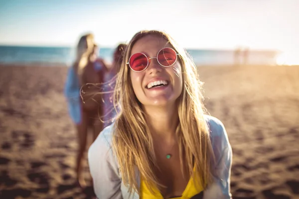 バックグラウンドで彼女の友人とビーチで幸せな若い女性。G — ストック写真