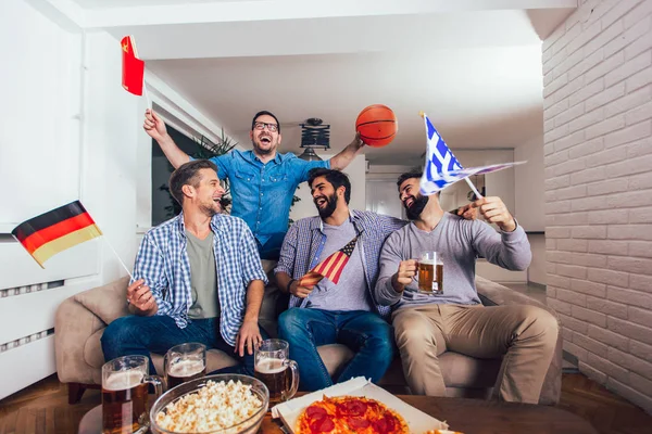 Happy friends or basketball fans watching basketball game on tv