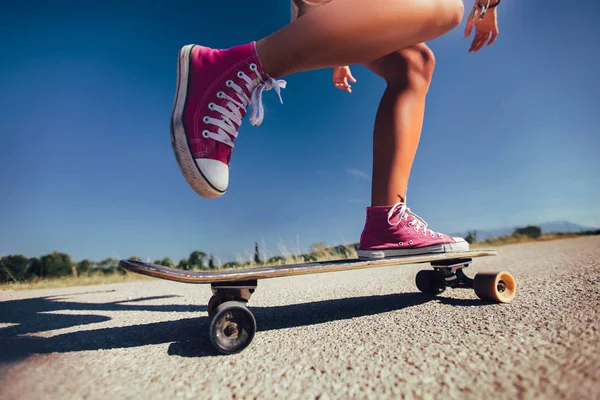 Close up de pés de uma menina de tênis vermelho montando no skatebo — Fotografia de Stock