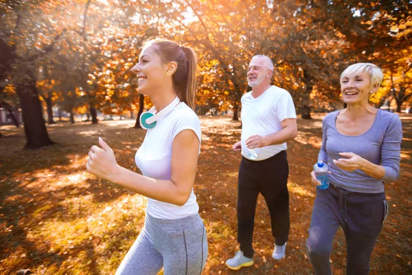 Senior man och kvinna och unga kvinnliga instruktör Workout på fre — Stockfoto