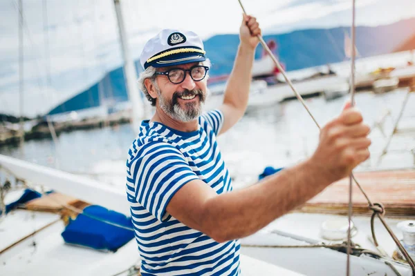 Homem maduro de pé e rindo do leme do veleiro no mar — Fotografia de Stock