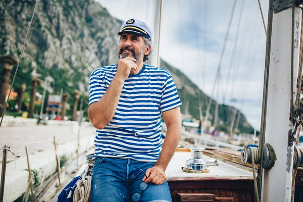 Reifer Mann steht lachend am Steuer eines Segelbootes auf hoher See — Stockfoto