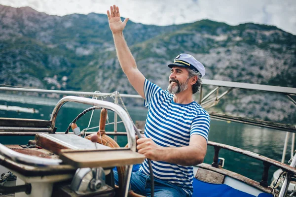 Volwassen man staande op helm van zeilboot uit op zee op een zonnige af — Stockfoto