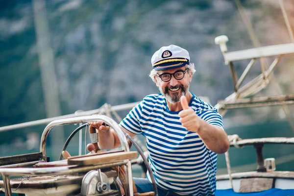 Volwassen man staan aan het roer van de zeilboot en wijst zijn duim omhoog — Stockfoto