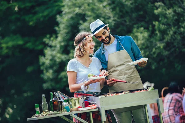 Unge venner har det sjovt grillning kød nyder grill fest . - Stock-foto