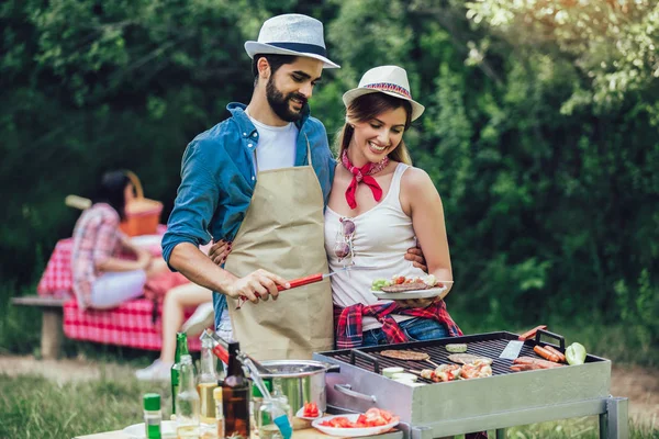 Jóvenes amigos divirtiéndose asando carne disfrutando de la fiesta barbacoa . — Foto de Stock