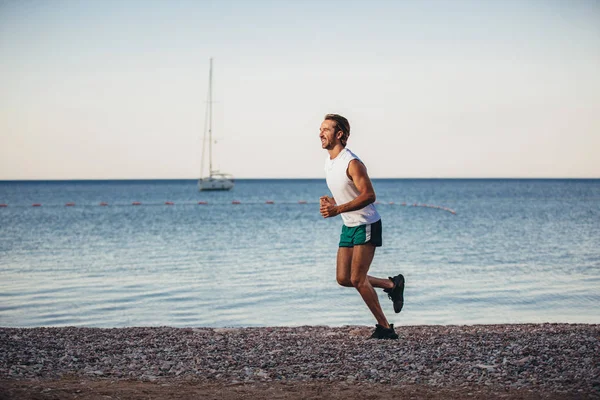 Hombre corriendo corriendo en la playa. Corredor masculino entrenamiento fuera worki — Foto de Stock