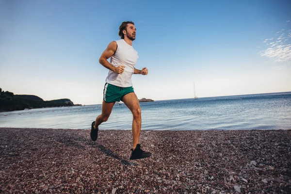 Bieganie człowiek jogging na plaży. Mężczyzna Runner szkolenia poza worki — Zdjęcie stockowe