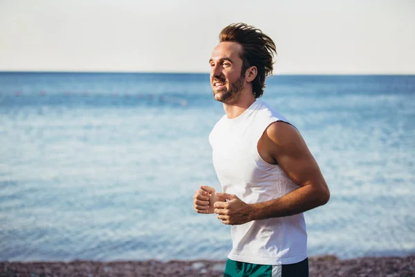 Bieganie człowiek jogging na plaży. Mężczyzna Runner szkolenia poza worki — Zdjęcie stockowe