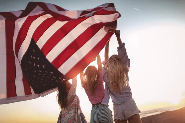 Junge Freunde mit amerikanischer Flagge am Strand — Stockfoto