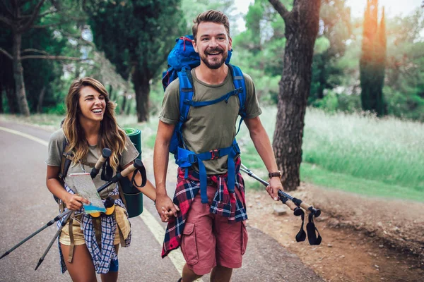 Sonriente pareja caminando con mochilas sobre fondo natural — Foto de Stock