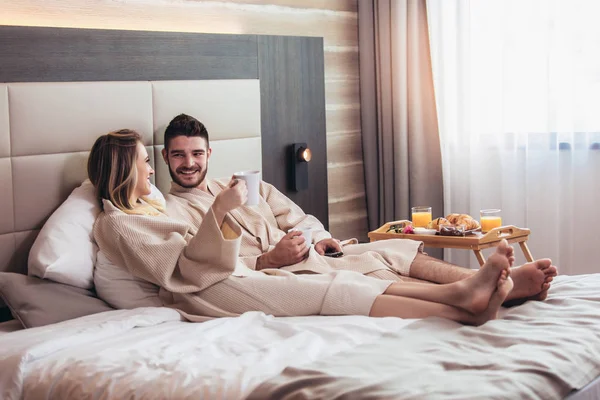 Giovane coppia felice fare colazione in camera d'albergo di lusso, watchi — Foto Stock