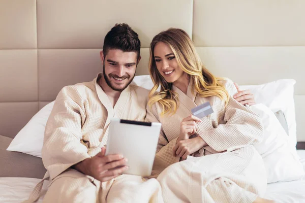 Joven pareja feliz compras en línea en habitación de hotel de lujo . — Foto de Stock