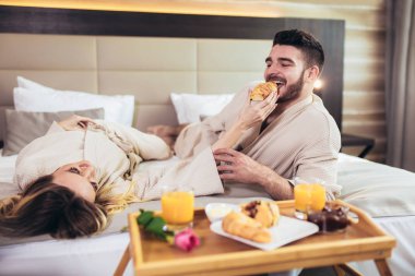 Lüks otel odasında kahvaltı eden genç mutlu çift. 