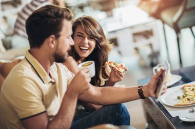 Bir restoranda pizza yiyen genç ve mutlu bir çift shot