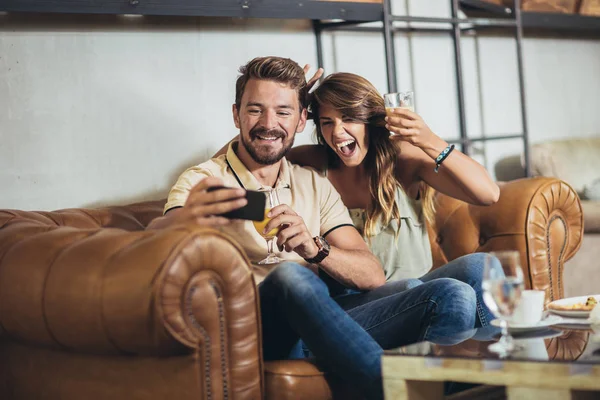 Hermosa pareja joven está haciendo selfie usando un teléfono inteligente y s — Foto de Stock