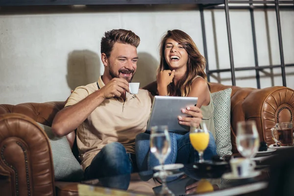 Junges Paar im Restaurant mit Blick auf digitales Tablet. — Stockfoto