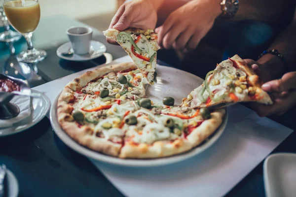 Pizza dilimi tutan insan elinin yakın çekim