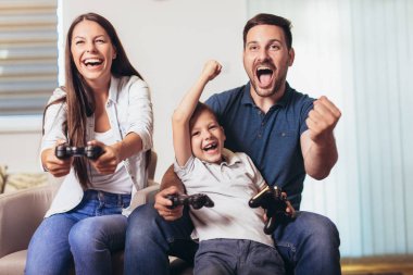 Aile birlikte video oyunları oynarken kanepede oturan gülümseyen