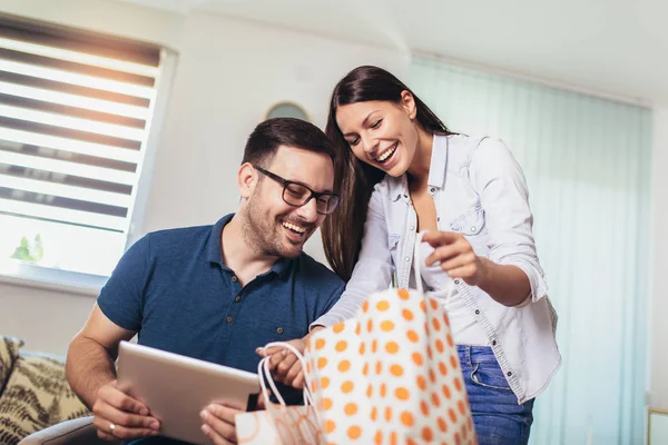 Gelukkig paar zittend op Bank met boodschappentas thuis — Stockfoto