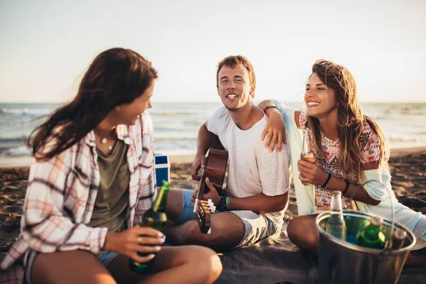 Amigos felizes festejando na praia com bebidas — Fotografia de Stock