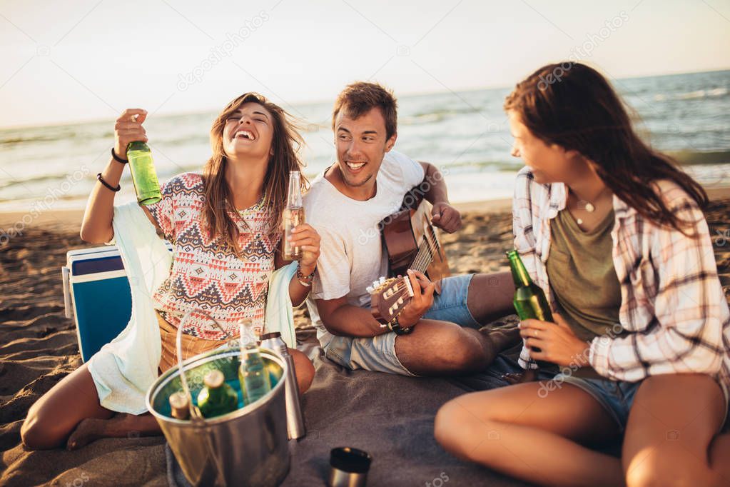 Happy friends partying on the beach with drinks