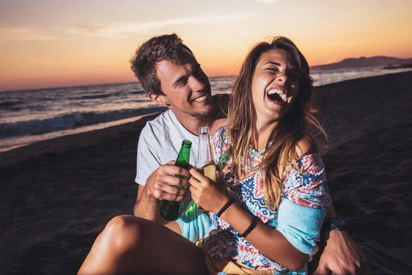 Jong koppel op het strand plezier, lachen en bier drinken — Stockfoto