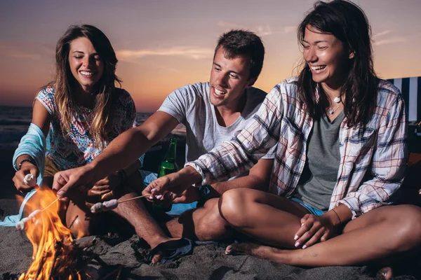 Amigos felizes festejando na praia com bebidas — Fotografia de Stock