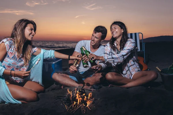 Lykkelige venner som fester på stranden med drinker – stockfoto