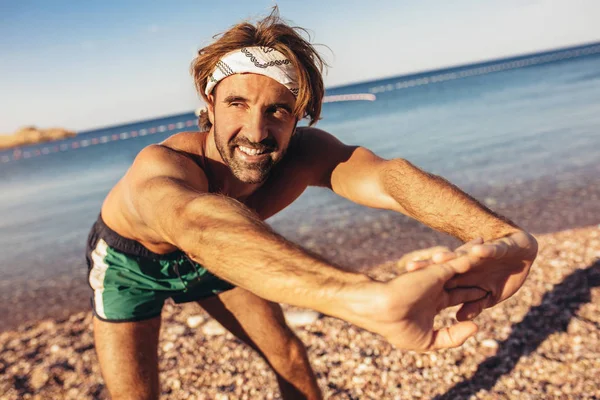 Runner doet Stretching oefeningen op een strand vroeg in de Mornin — Stockfoto