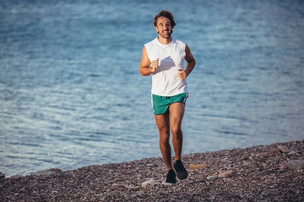 Un joven entrenando en la playa por la mañana. Joven por la mañana — Foto de Stock