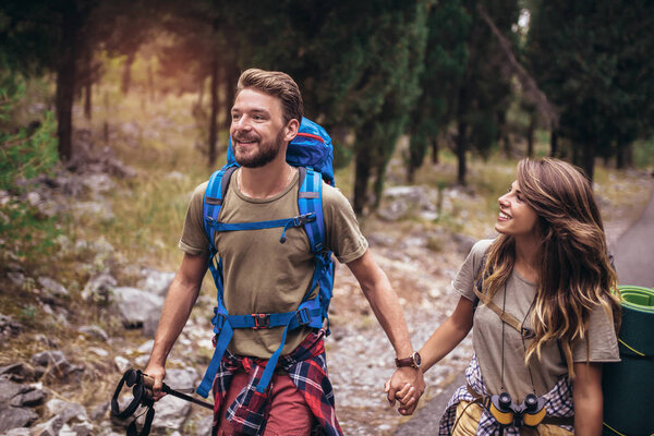 Romantic couple hiking trought forest.