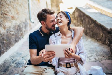 Merdivenlerde dijital tablet kullanan romantik turist çifti.