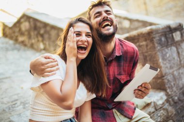 Merdivenlerde dijital tablet kullanan romantik turist çifti.