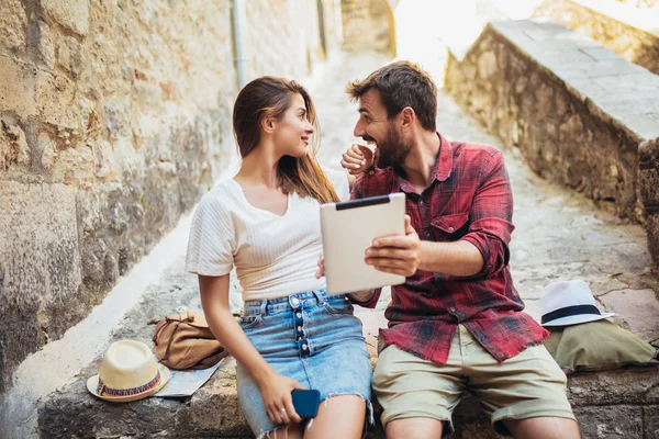 Romantisches Touristenpaar sitzt mit digitalem Tablet auf Treppe. — Stockfoto
