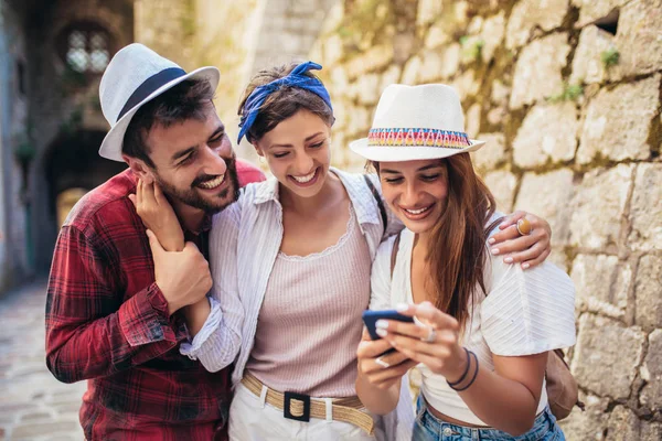 Grupo feliz de turistas que viajam e passeios usando telefone . — Fotografia de Stock
