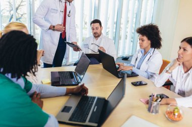 Tıbbi ekip oturma ve ofiste masada tartışıyor.