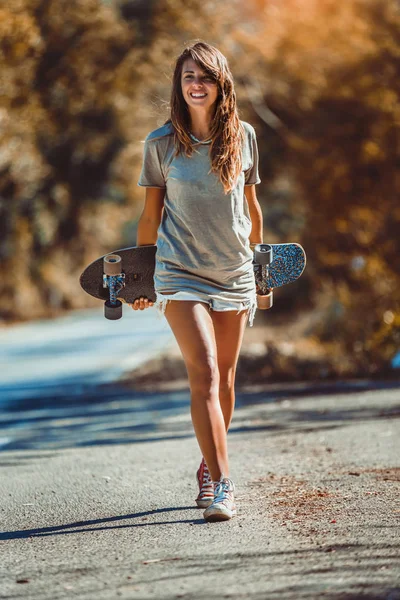 Mooi en mode jong vrouw poseren met een skateboard — Stockfoto