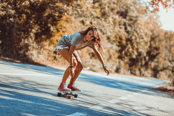 Jonge sportieve vrouw rijden op het skateboard op de weg. — Stockfoto