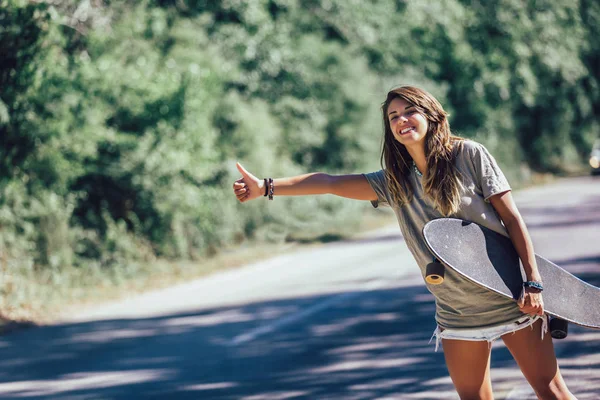 Skate menina carona e parar carro com polegares para cima gest — Fotografia de Stock