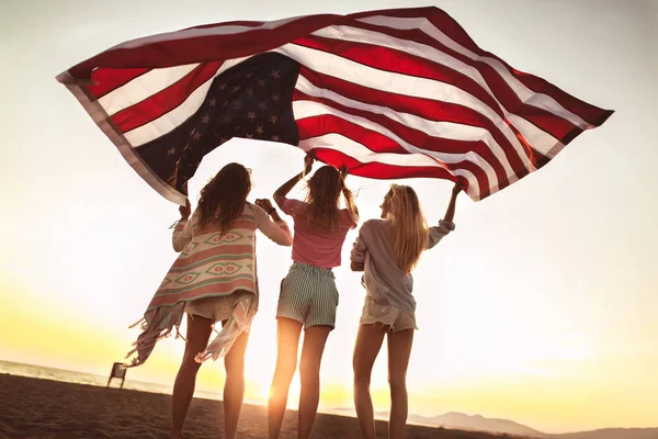 Junge Freunde mit amerikanischer Flagge am Strand — Stockfoto